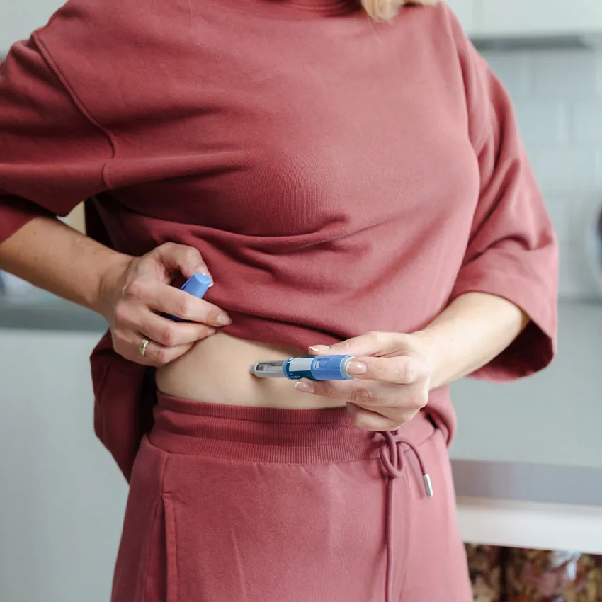 Woman injecting insulin with an insulin pen into abdomen for diabetes management