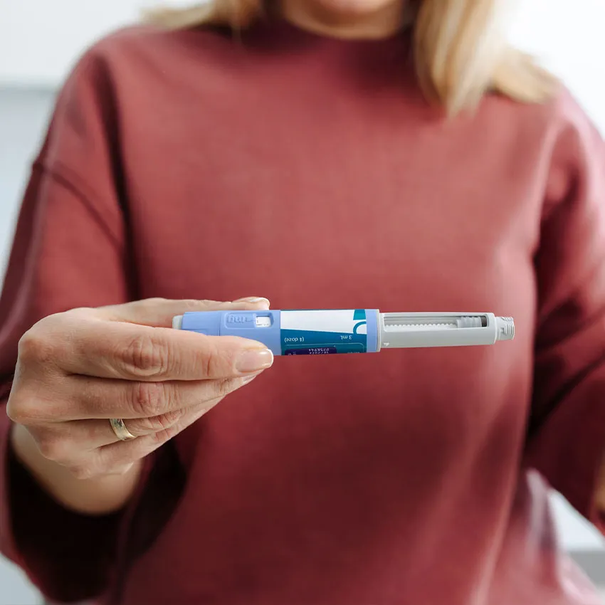 Woman holding blue insulin pen injector in hand, close-up for diabetes management