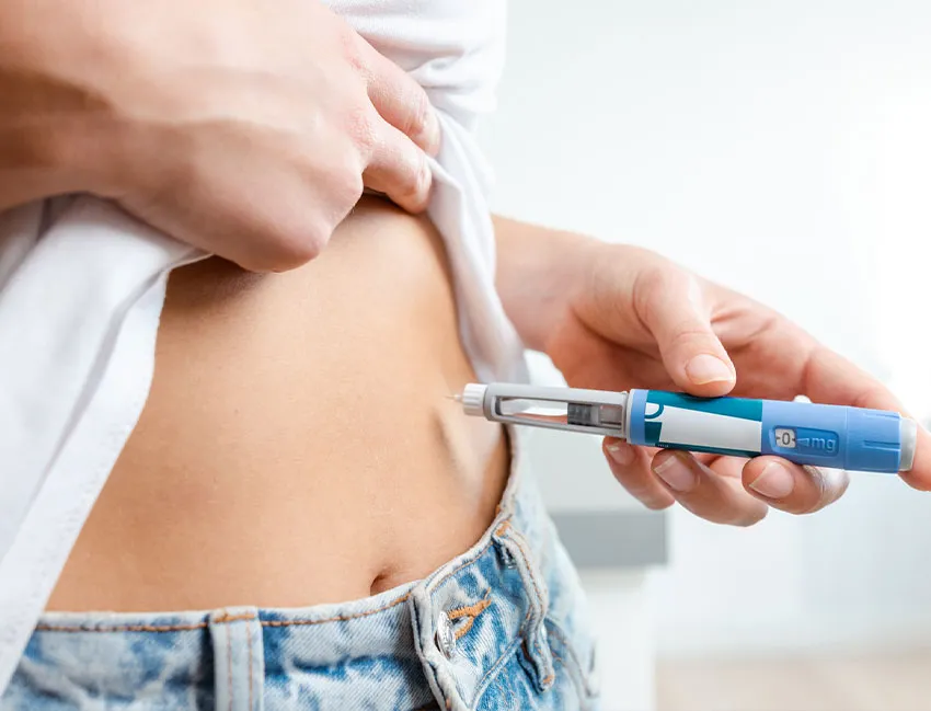 A person self-administering an insulin pen injection to the abdomen for diabetes management